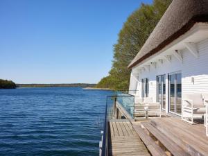 a house with a deck with chairs on the water at Doppelhaushälften im Naturresort Drewitz in Drewitz