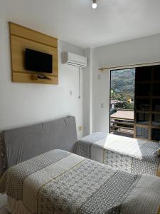 a bedroom with two beds and a tv on the wall at Residencial Vista Bela in Bombinhas