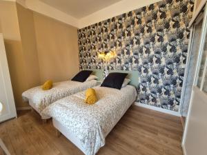 two beds in a room with a wall with birds on it at Studio face au lac in Bagnoles de l'Orne