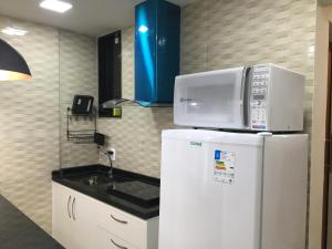 a microwave on top of a refrigerator in a kitchen at VieiraNunes Flats in Rio de Janeiro