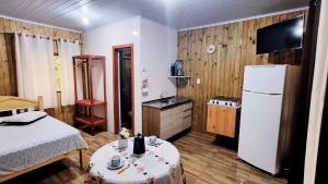 a kitchen with a refrigerator and a table in a room at Cabana Cristal ll Campestre Em Sítio ll Wi-Fi Nômade Digital ll Táxi Fácil II Forno Microondas ll Quiosque Churrasqueira ll 6km da Estrada do Mar ll 8,1Km Prefeitura II 7,2Km UFRGS Litoral II 12km do Morro da Borrusia e das Praias Tramandai in Osório