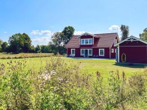 a red house with a garage in a field at 8 person holiday home in LÖTTORP-By Traum in Löttorp