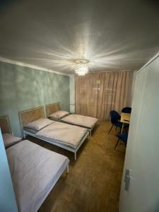 two beds in a room with a table and chairs at Mieszkaj u Marty stale na Stałym in Jaworzno