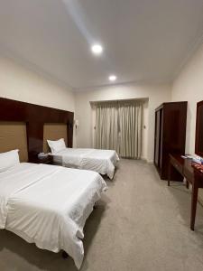 a hotel room with two beds and a desk at شقق زائر الشمال للشقق المخدومه in Sakakah