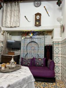 a living room with a purple couch and a clock at DarMouniaFès in Fez