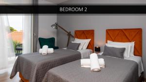 deux lits dans une chambre d'hôtel avec deux chaises dans l'établissement APARTMENTS4YOU SUPETAR 5 - brand NEW luxury 2-BR - 200 meters from the beach - free parking - beautiful terrace, à Supetar