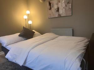 a white bed in a bedroom with two lights at Secluded cosy extension with free parking, sleeps 4 in Blackwater