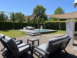 a patio with two chairs and a table and a pool at De Madelief 6-persoons in Lievelde