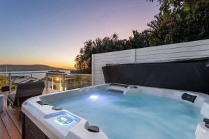 a hot tub on a deck with the sunset in the background at The Peak of Mt Martha Spa and Sunset Views in Mount Martha