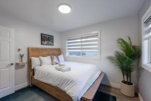 a bedroom with a bed with white sheets and a plant at Contemporary Alaska 2-bedroom Apartment in Juneau