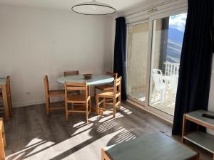 ein Wohnzimmer mit einem Tisch und Stühlen sowie einem großen Fenster in der Unterkunft Résidence Balcons Du Soleil 1 - T3/6pers BALCONS DU SOLEIL 63- Peyresourde MAE-9544 in Germ