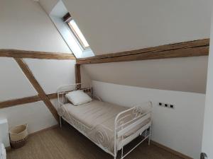 a bedroom with a white bed in a attic at Charmante maison alsacienne, sauna et jardin in Châtenois