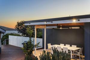 a patio with a table and chairs on a deck at The Peak of Mt Martha Spa and Sunset Views in Mount Martha