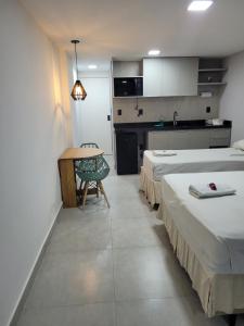 a room with two beds and a table and a kitchen at Victory Flat&Hotel in João Pessoa