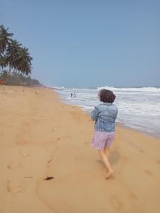 a woman is walking on the beach at Iroko Plage San Pédro in San-Pédro