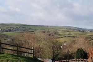 une vue d'un champ avec des éoliennes au loin dans l'établissement Bwlch Cottage, à Gwaynynog 3 autres photos