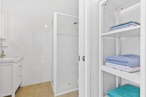 a white bathroom with a shower and towels at The Treehouse at Long Beach in Long Beach
