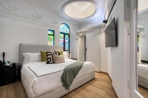 ein Schlafzimmer mit einem großen weißen Bett und einem Fernseher in der Unterkunft UTOPIC Campos Elíseos by ULIV in Mexiko-Stadt
