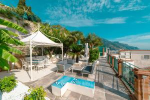 un patio con tavolo e sedie e una piscina di Luxury Seaview Villa with Jacuzzi, Sauna & Gym in Amalfi Coast - Villa Dorotea a Minori