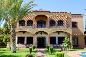 a large house with a balcony and a palm tree at Les Terrasses Des Jardins in Marrakech
