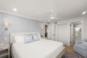 a white bedroom with a bed and a chair at Serenity Shores Renovated Top Floor Condo w Stunning Ocean Views in New Smyrna Beach +46 photos
