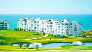 a large white building on a golf course next to the ocean at la perle du nord by marina golf asilah in Asilah
