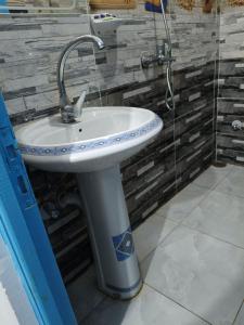 La salle de bains est pourvue d'un lavabo blanc et d'une douche. dans l'établissement Mido Nubian Guesthouse, à Assouan