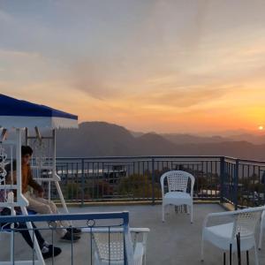 a man sitting on a balcony with a view of the mountains at Naldehra House Hotel in Nāldera