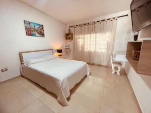 een witte slaapkamer met een bed en een raam bij Hostal los profes in Mocoa