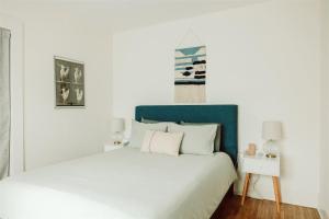 a white bedroom with a bed with a blue headboard at Walk to Beach - Beach Gear - Easy Parking in Long Beach +66 photos
