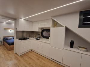eine Küche mit weißen Schränken und ein Bett in einem Zimmer in der Unterkunft Hausboot -Berlin WaterBliss in Berlin