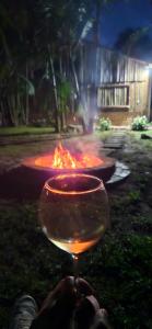 a person holding a wine glass in front of a fire pit at Cabana Du Sítio in Praia Grande