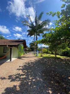 a house with a palm tree next to a road at Suites da Rota - Pomerode SC in Pomerode