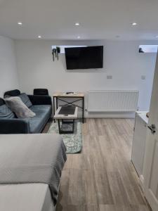 ein Wohnzimmer mit einem Sofa und einem Fernseher an der Wand in der Unterkunft Modern self contain studio Own Private Access in Finchley