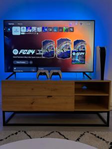 TV de pantalla plana en la parte superior de un centro de entretenimiento de madera en Central Leeds - Stylish Apartment, en Leeds