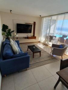 a living room with a blue couch and a tv at Departamento Laguna del Mar in La Serena