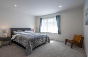 a bedroom with a bed and a window and a chair at Beckenham Garden in Auckland