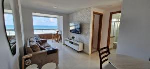 a living room with a couch and a television and the ocean at COPFL0109 - Condomínio Residencial Ilha de Maiorca in Salvador