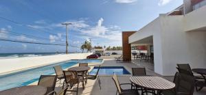 a patio with tables and chairs next to the beach at COPFL0109 - Condomínio Residencial Ilha de Maiorca in Salvador