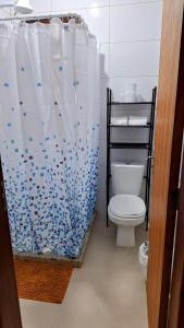 a bathroom with a toilet and a shower curtain at Recanto do surf in Imbituba