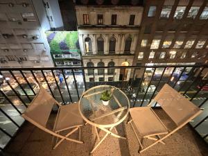 a glass table and chairs on a balcony with a building at Apartamento BA Obelisco in Buenos Aires