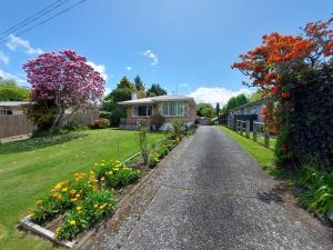 una casa con un jardín de flores en un patio en 3 Bedroom Home by the Reserve, en Rotorua