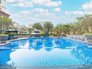 a swimming pool at a resort with palm trees at DLG Hotel Danang in Da Nang