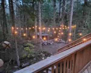 a deck with a lit up forest with christmas lights at Shelter Chalet in Rhododendron