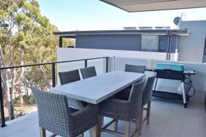 a table and chairs on a balcony with a grill at 301 The Lookout in South West Rocks