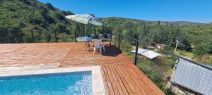 una terrazza in legno con tavolo e ombrellone di CABAÑAS CAMPO CHICO a Trapiche