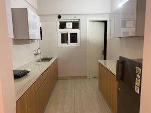 Una cocina con gabinetes blancos y un refrigerador negro. en Tara Luxury Homes 2BHK, en Solan