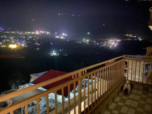 Un mono sentado en lo alto de un balcón por la noche. en Tara Luxury Homes 2BHK, en Solan