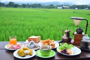 a table with plates of breakfast food and a field at บ้านฮิมนาปัวรีสอร์ท in Pua