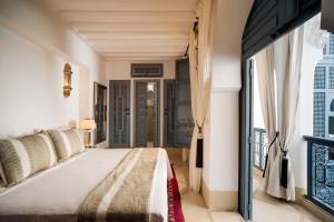 a hotel room with two beds and a large window at Riad Adore in Marrakesh